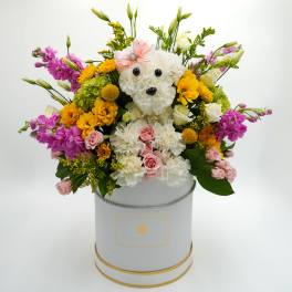 Flower arrangement in a hatbox with a teddy bear face made of white blooms