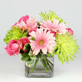 Pink roses and gerbera daisies in a clear square vase