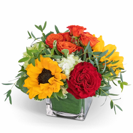 Mixed bouquet with roses and sunflowers in a square glass vase