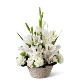 All-white flower basket with tall blooms arranged in a woven white basket.