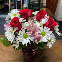 Red roses and white daisies in a dark glass vase