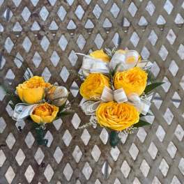 Two yellow rose boutonnieres with white ribbon bows