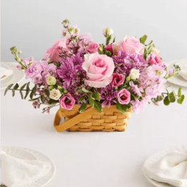 Pink and purple flower arrangement in a woven basket