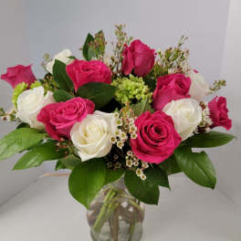 Pink and white roses arranged in a clear glass vase