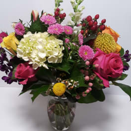 Mixed bouquet of pink, white, yellow, and orange flowers in a glass vase