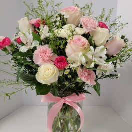 Pink and white mixed bouquet in a glass vase with a pink ribbon
