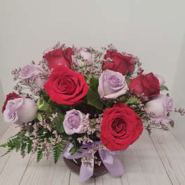 Bouquet of red and lavender roses in a vase with a ribbon