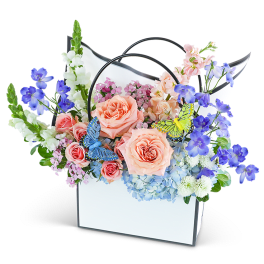 Pastel flower arrangement in a white handled box with butterfly accents