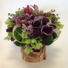 Purple calla lilies and mixed blooms in a birch bark container