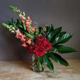 Red chrysanthemums and pink snapdragons in a clear glass vase