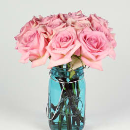 Pink roses arranged in a blue glass mason jar