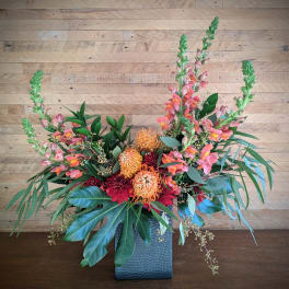 Colorful floral arrangement in a textured blue vase with tall pink spikes