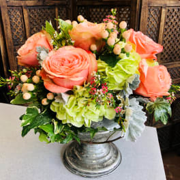 Peach roses and green hydrangeas in a silver pedestal vase