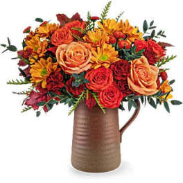 Bouquet of orange and red flowers in a brown pitcher vase