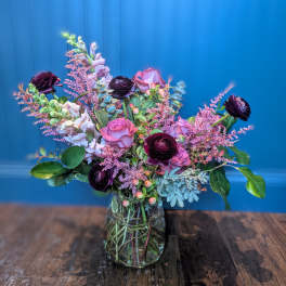 Mixed bouquet of pink and dark purple flowers in a glass vase
