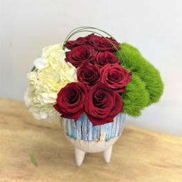 Red roses with white hydrangea and green moss in a decorative vase