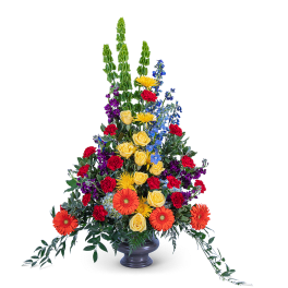 Tall mixed flower arrangement in a gray vase with orange, yellow, red, blue, and purple blooms