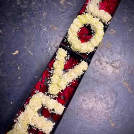 Long floral box with cream roses arranged as letters over red petals