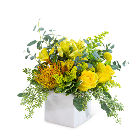 Yellow floral arrangement in a white square vase