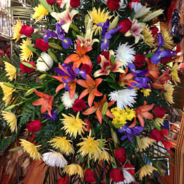 Large mixed floral spray with red roses, lilies, and yellow and white blooms
