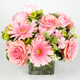 Pink roses and gerbera daisies in a square glass vase