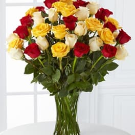 Bouquet of red, yellow, and white roses in a clear glass vase