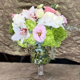 Bouquet of white and pink flowers in a clear stemmed vase