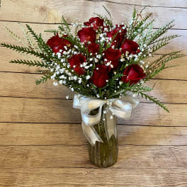 Red roses in a glass vase with white baby's breath and a ribbon bow