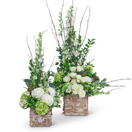 Two tall floral arrangements with white roses and green blooms in birch containers