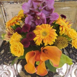 Bouquet with purple orchids, yellow roses, orange calla lilies, and mixed daisies
