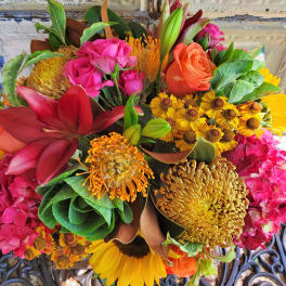 Mixed bouquet with roses, lilies, sunflowers, and orange pincushion blooms
