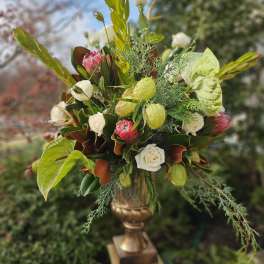 Tall floral arrangement with white roses and pink protea in a gold vase