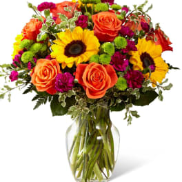 Bouquet of orange roses and yellow sunflowers in a glass vase