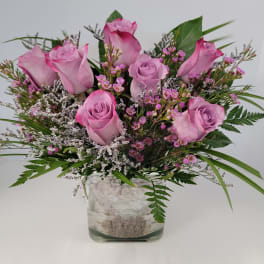 Pink roses arranged in a clear glass vase with small filler flowers