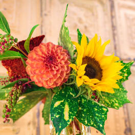 Bouquet with a coral dahlia and yellow sunflower in a glass vase