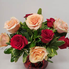 Bouquet of peach and red roses in a red glass vase