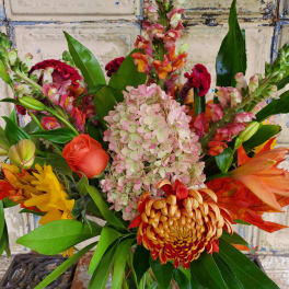 Mixed bouquet with pink hydrangea, orange roses, and tropical blooms