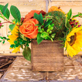Orange rose and sunflowers in a wooden box with greenery