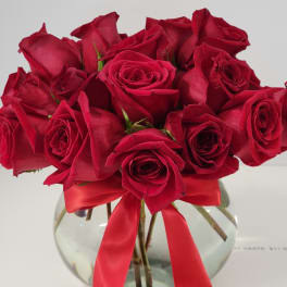 Bouquet of red roses in a clear glass vase with a red ribbon
