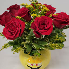 Red roses arranged in a yellow smiley-face vase