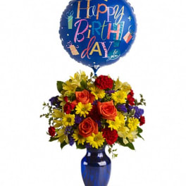 Birthday balloon above a colorful flower arrangement in a blue vase