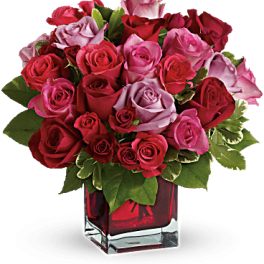 Bouquet of red, pink, and lavender roses in a red glass vase
