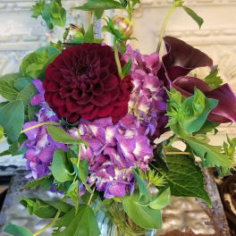 Bouquet of purple flowers with dark burgundy blooms in a glass vase
