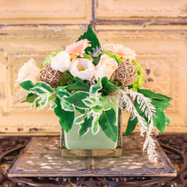Floral arrangement in a square glass vase with white and peach blooms