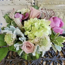 Mixed bouquet of pink roses, hydrangea, and white blooms in a glass vase