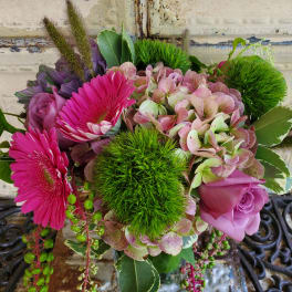 Pink gerberas and roses with hydrangea and green pom-pom blooms in a vase