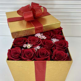 Gold gift box filled with red roses and small pink flowers