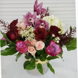Bouquet of pink orchids, red and pink roses, and white hydrangea in a vase