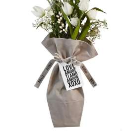 White tulip bouquet with white filler flowers wrapped in beige fabric with XOXO ribbon and love message tag.