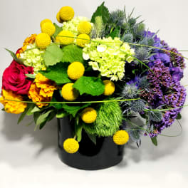 Colorful mixed bouquet in a black vase with yellow, purple, and red blooms